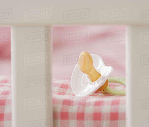 Close up of pacifier in crib Stock Photo Dissolve