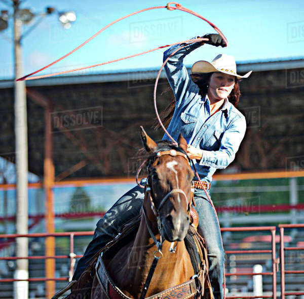 Caucasian cowgirl on horse throwing lasso in rodeo on ranch Stock