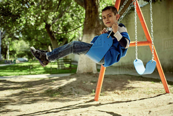 Hispanic boy on swing at park - Royalty-free Stock Photo | Dissolve