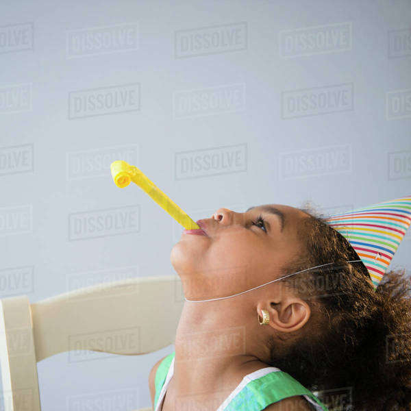 African American girl blowing noisemaker at birthday party Stock