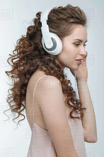 Side view of attractive young woman listening music in headphones
