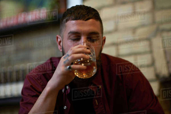 Young Man With Tattooed Fingers Drinking Tumbler Of Spirit In Public House Stock Photo Dissolve