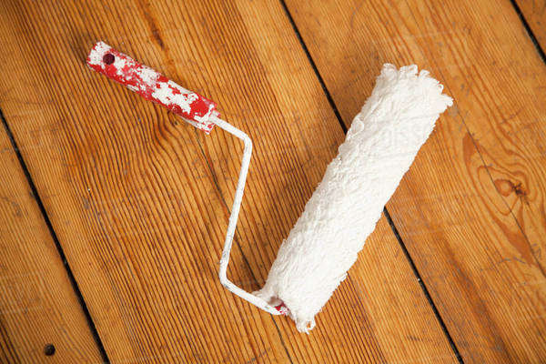 A paint roller on a hardwood floor, directly above - Stock Photo - Dissolve