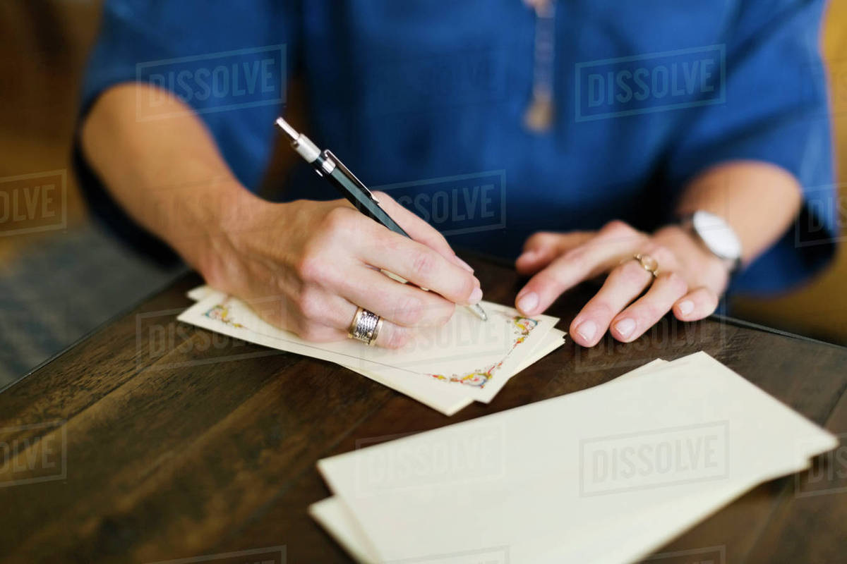 Close-up of woman writing letter - Stock Photo - Dissolve