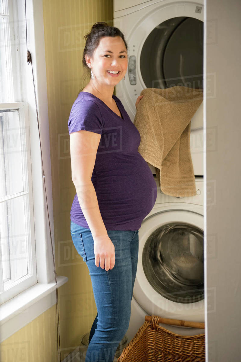Pregnant woman doing laundry Stock Photo Dissolve
