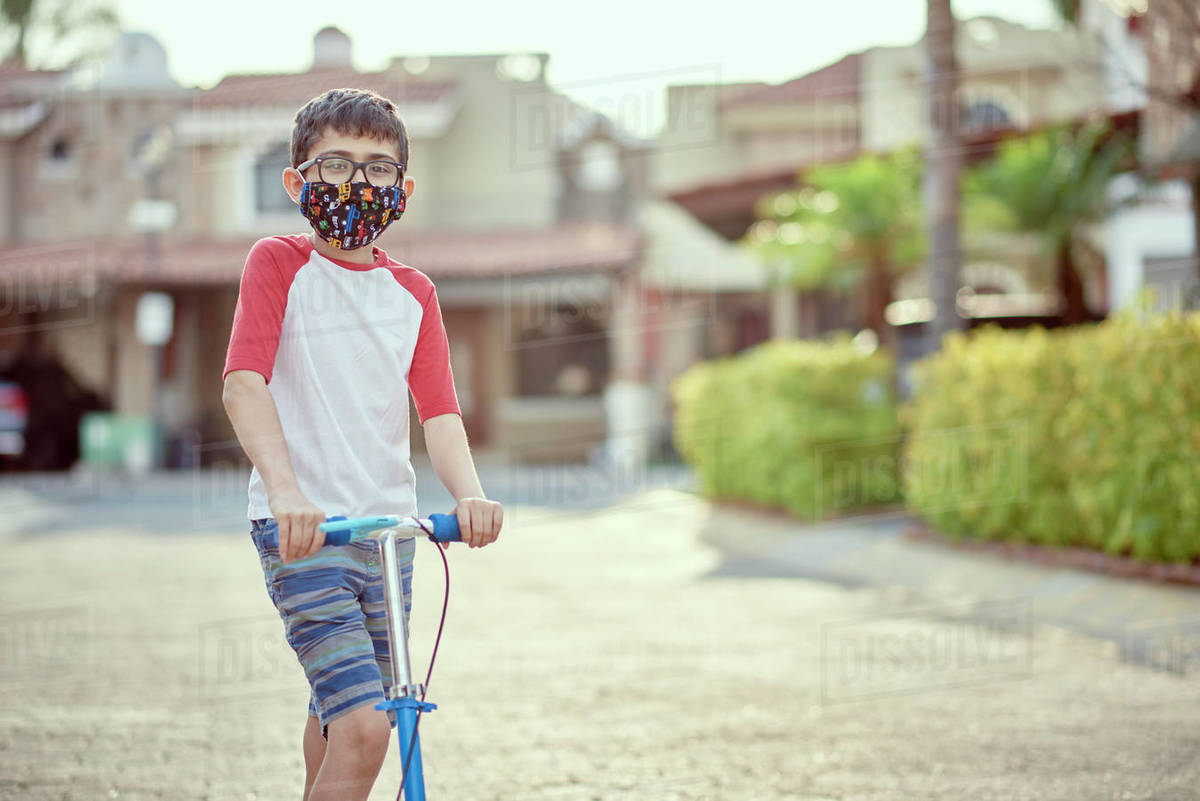 Mexico, Zapopan, Boy with face mask riding scooter Royalty-free stock photo