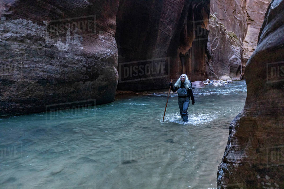 United States, Utah, Zion National Park, Senior female hiker wading The