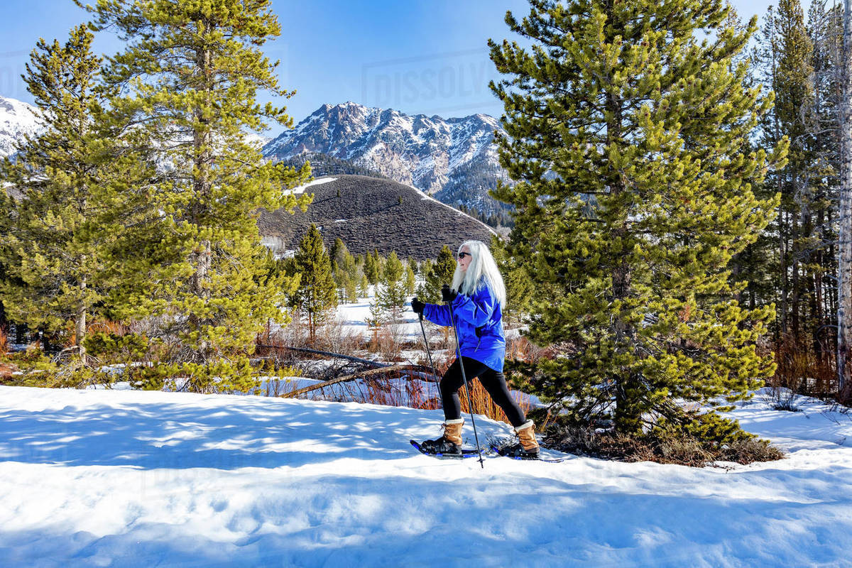 USA, Idaho, Ketchum, Senior blonde woman snowshoeing in snow covered
