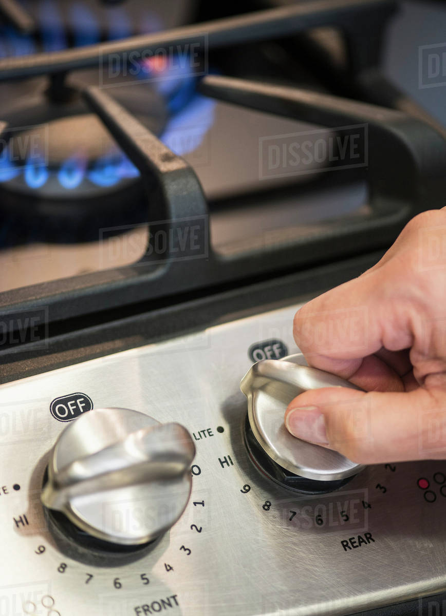 Closeup of hand adjusting stove burner Stock Photo Dissolve