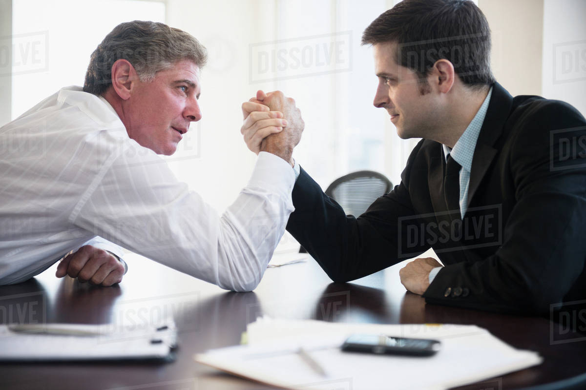 Office workers wrestling on desk Stock Photo Dissolve
