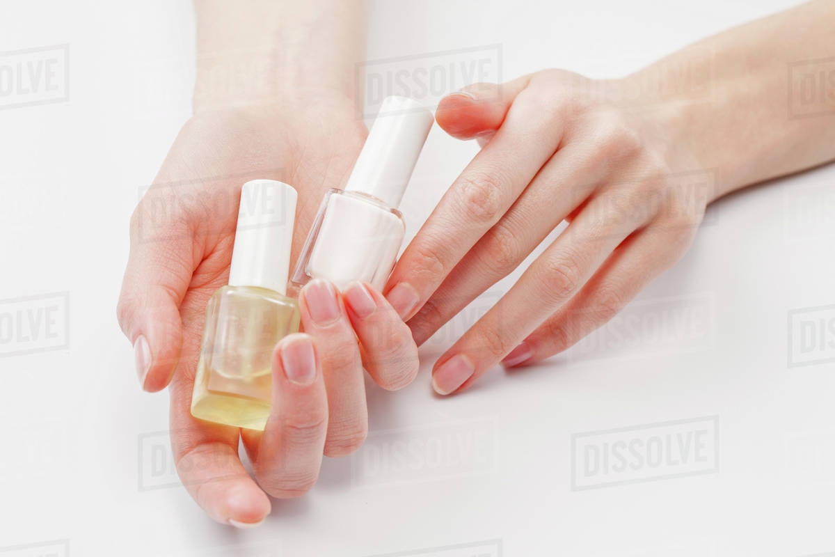 Close up of woman's hands holding nail polish, studio shot Stock