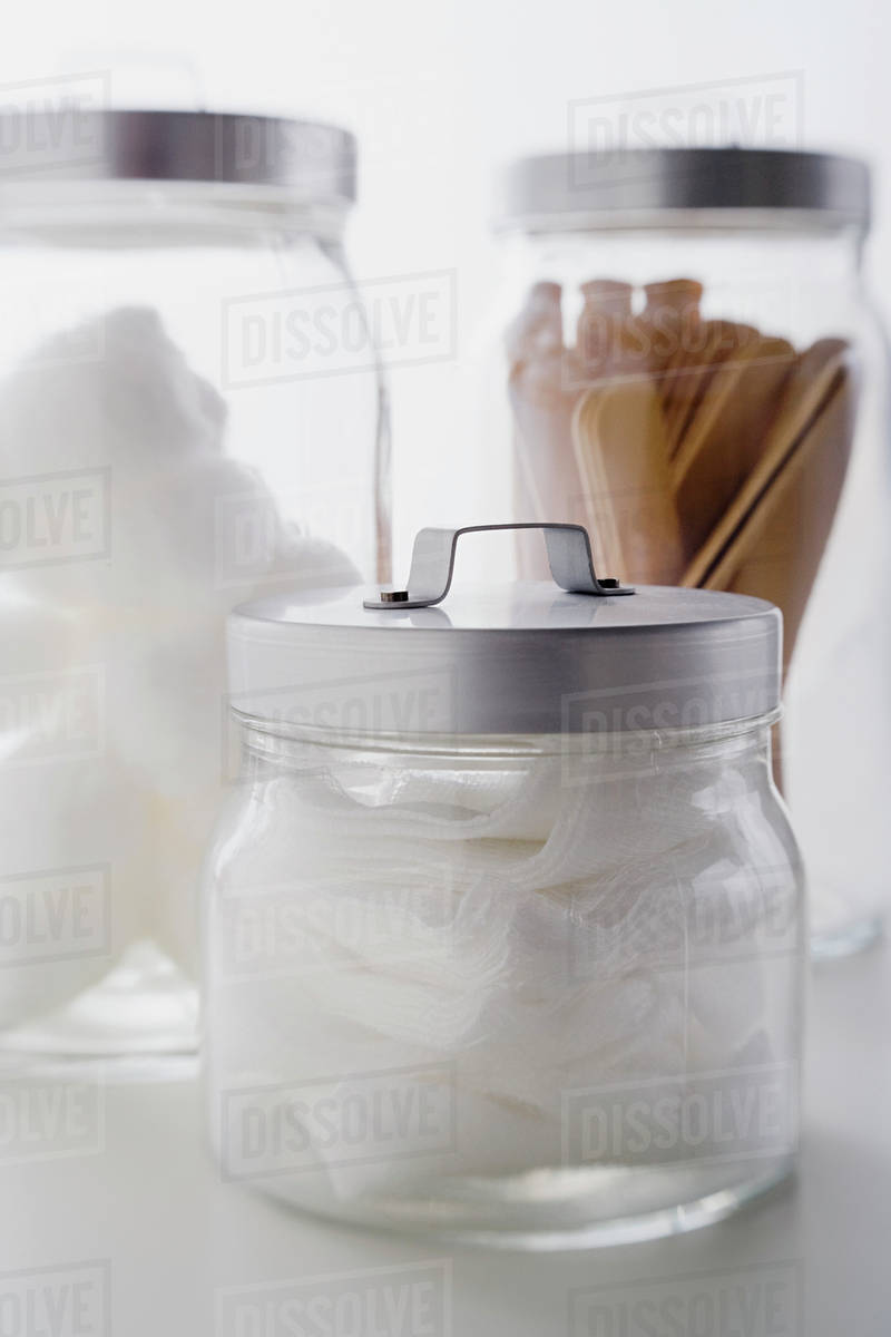 Close up of gauze and spatulas in jars studio shot Stock Photo Dissolve