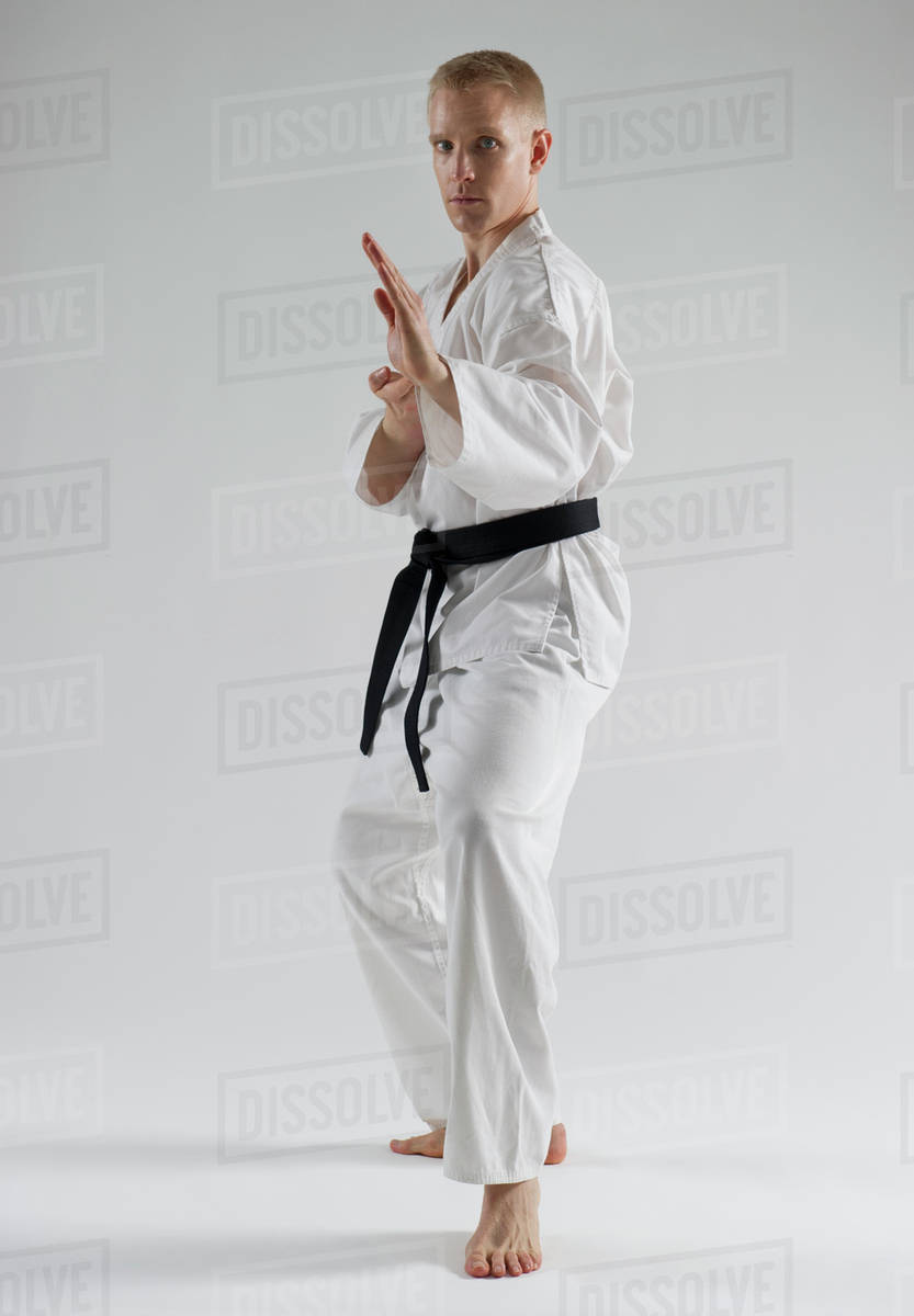 Young man performing karate stance on white background Stock Photo