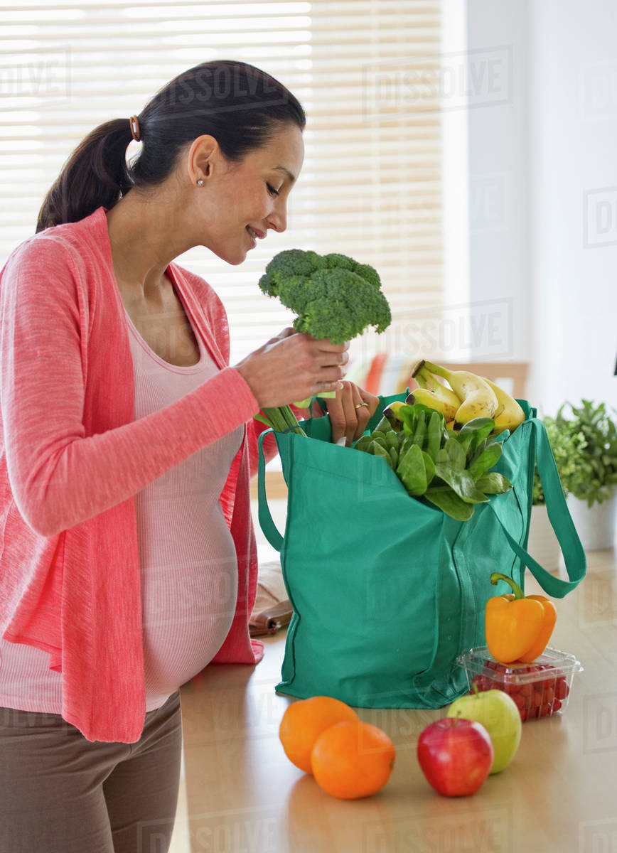 Pregnant woman unpacking groceries Stock Photo Dissolve