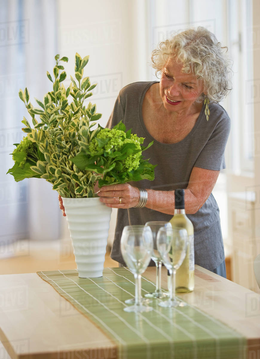 Woman arranging flowers in a vase Stock Photo Dissolve