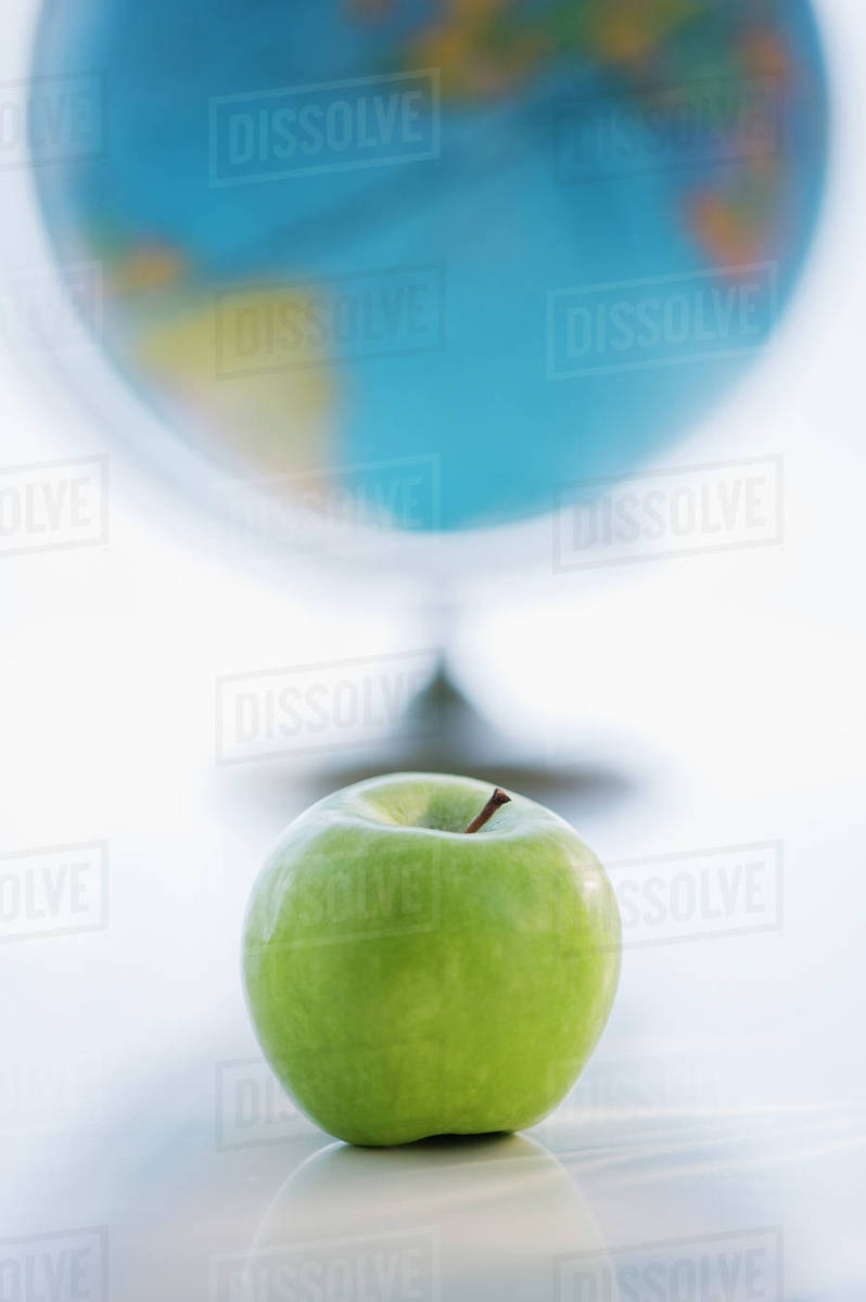 Green apple with globe in background - Stock Photo - Dissolve