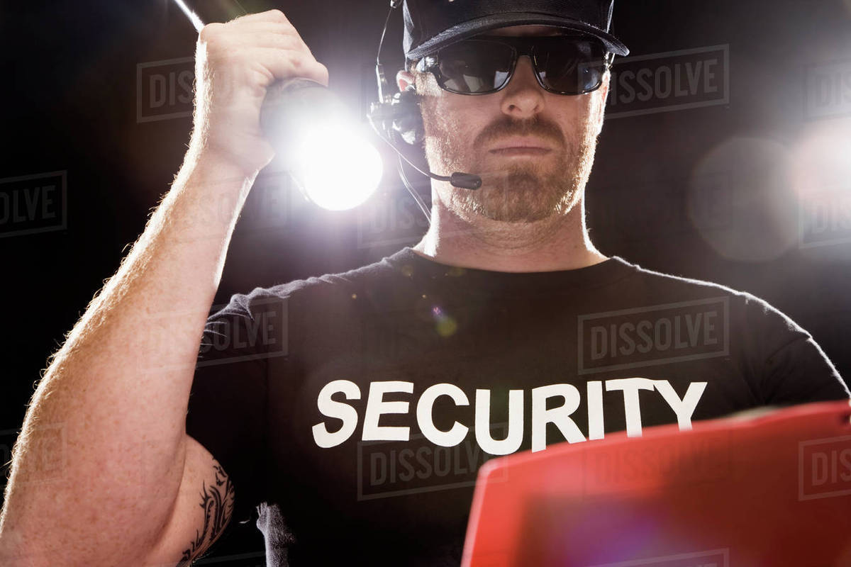 Bouncer looking at guest list with flashlight Stock Photo Dissolve