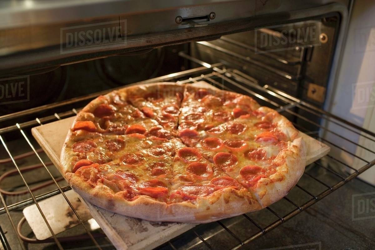 Warming up pepperoni pizza in oven Stock Photo Dissolve