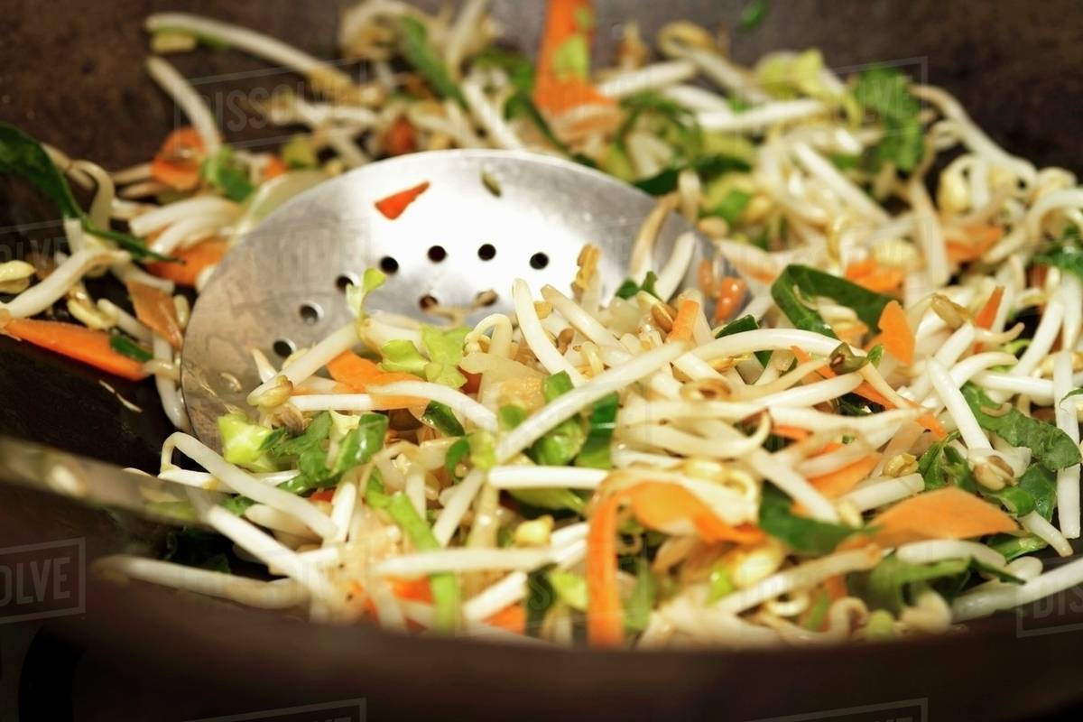 Frying vegetables in wok (closeup) Stock Photo Dissolve