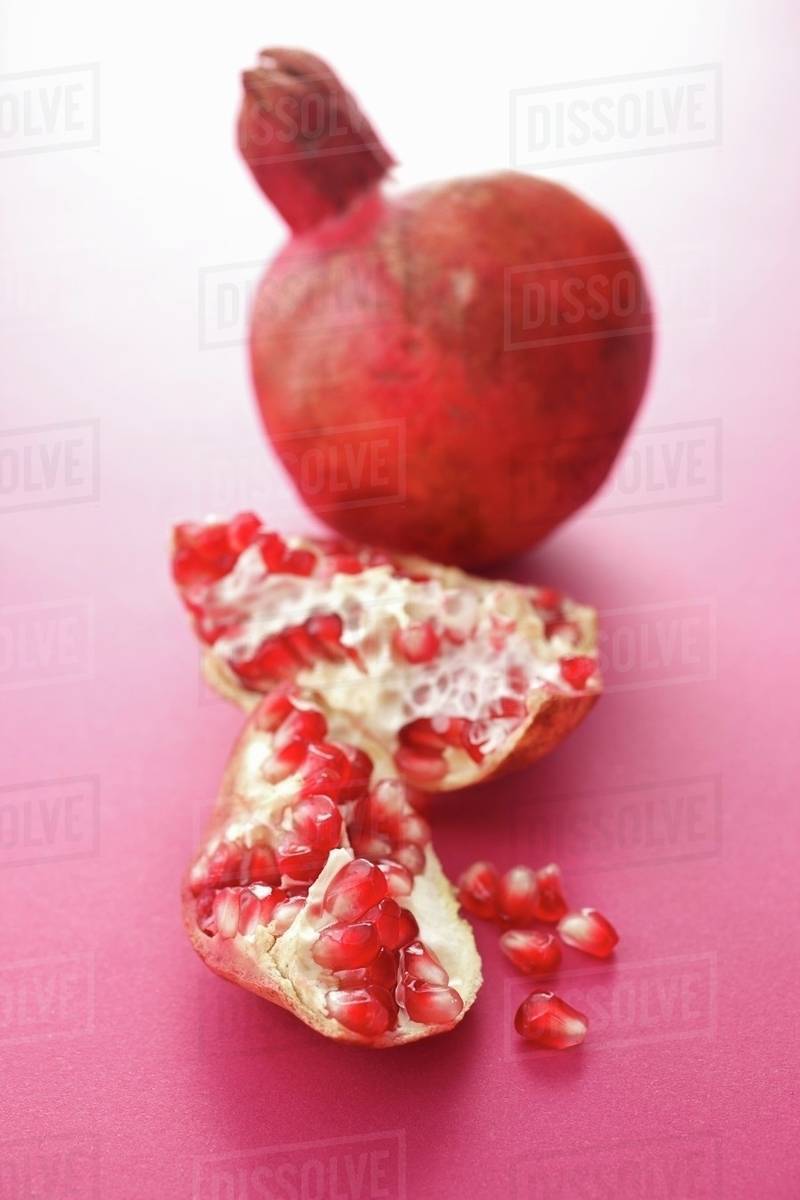 Whole pomegranate and pieces of pomegranate Stock Photo Dissolve