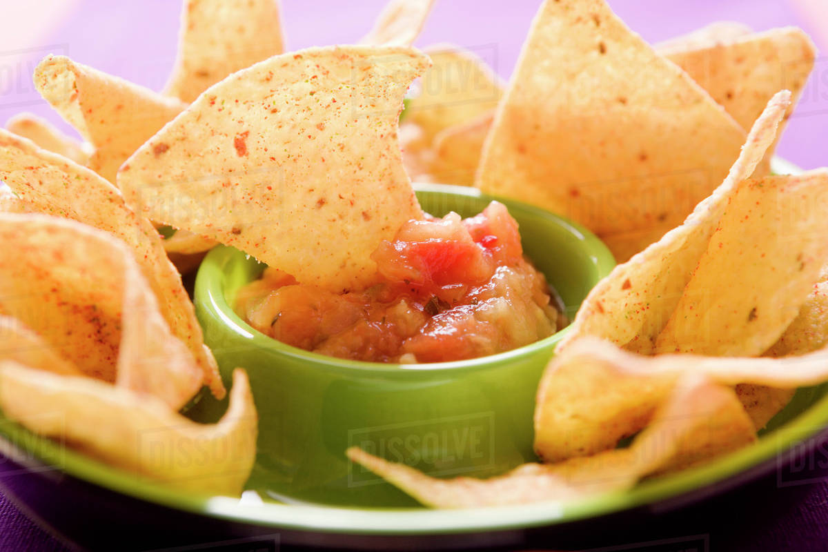 Tortilla chip dipped in tomato salsa Stock Photo Dissolve