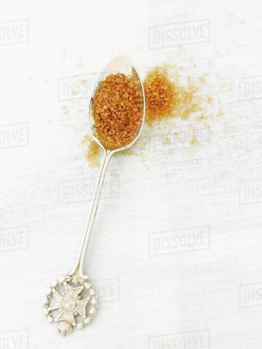 Demerara sugar on silver spoon Stock Photo Dissolve