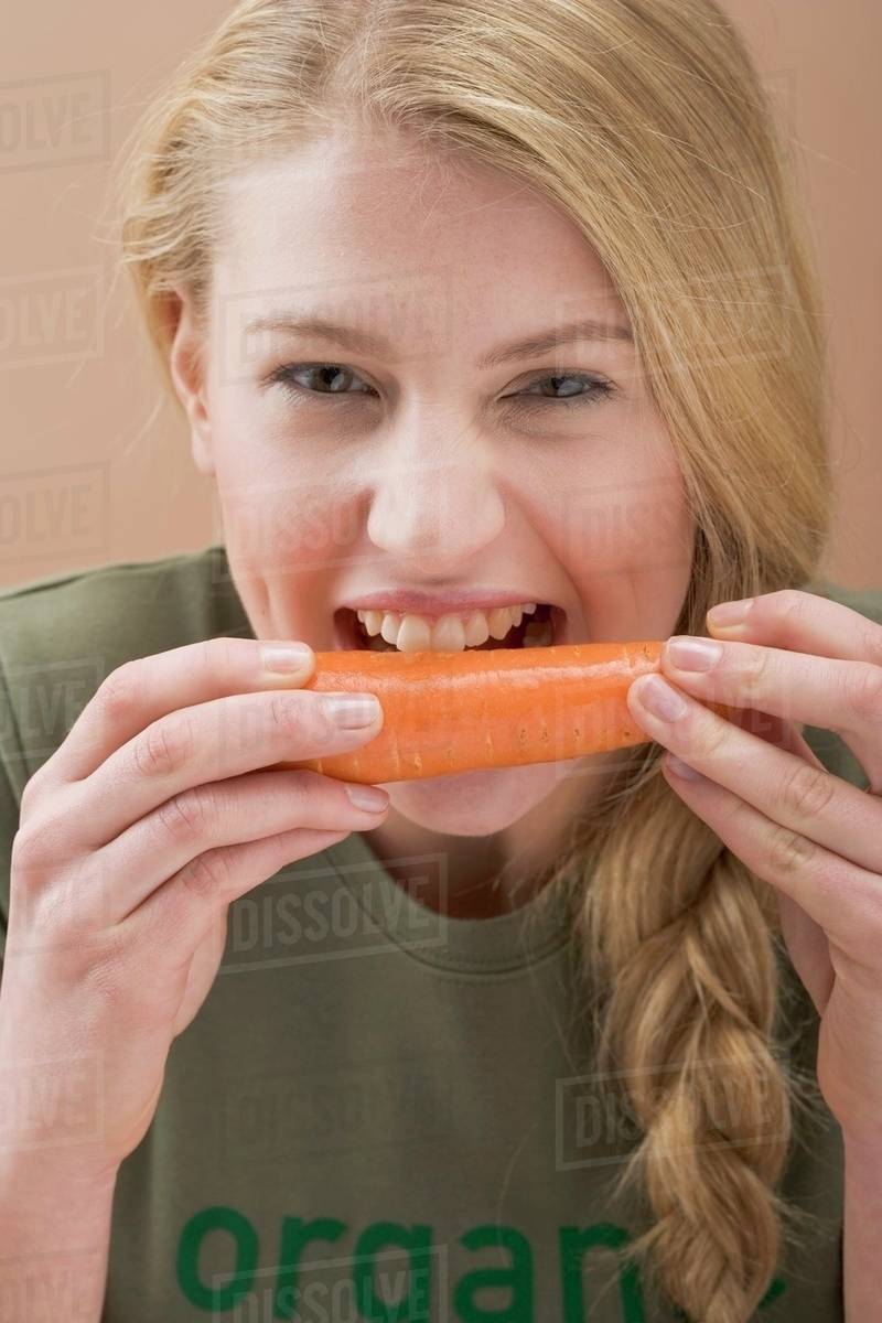 Woman biting a fresh carrot Stock Photo Dissolve