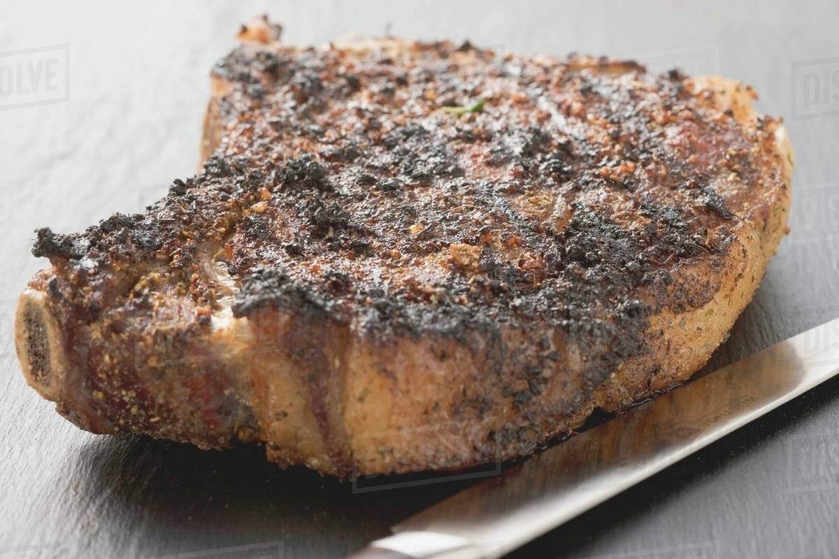 Spicy fried rib eye steak, bonein Stock Photo Dissolve