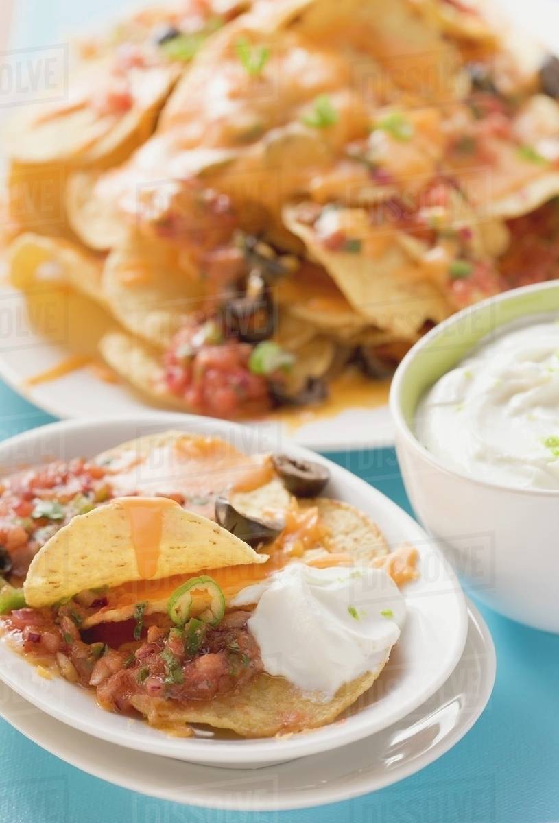 Tortilla chips with melted cheese, olives and sour cream Stock Photo