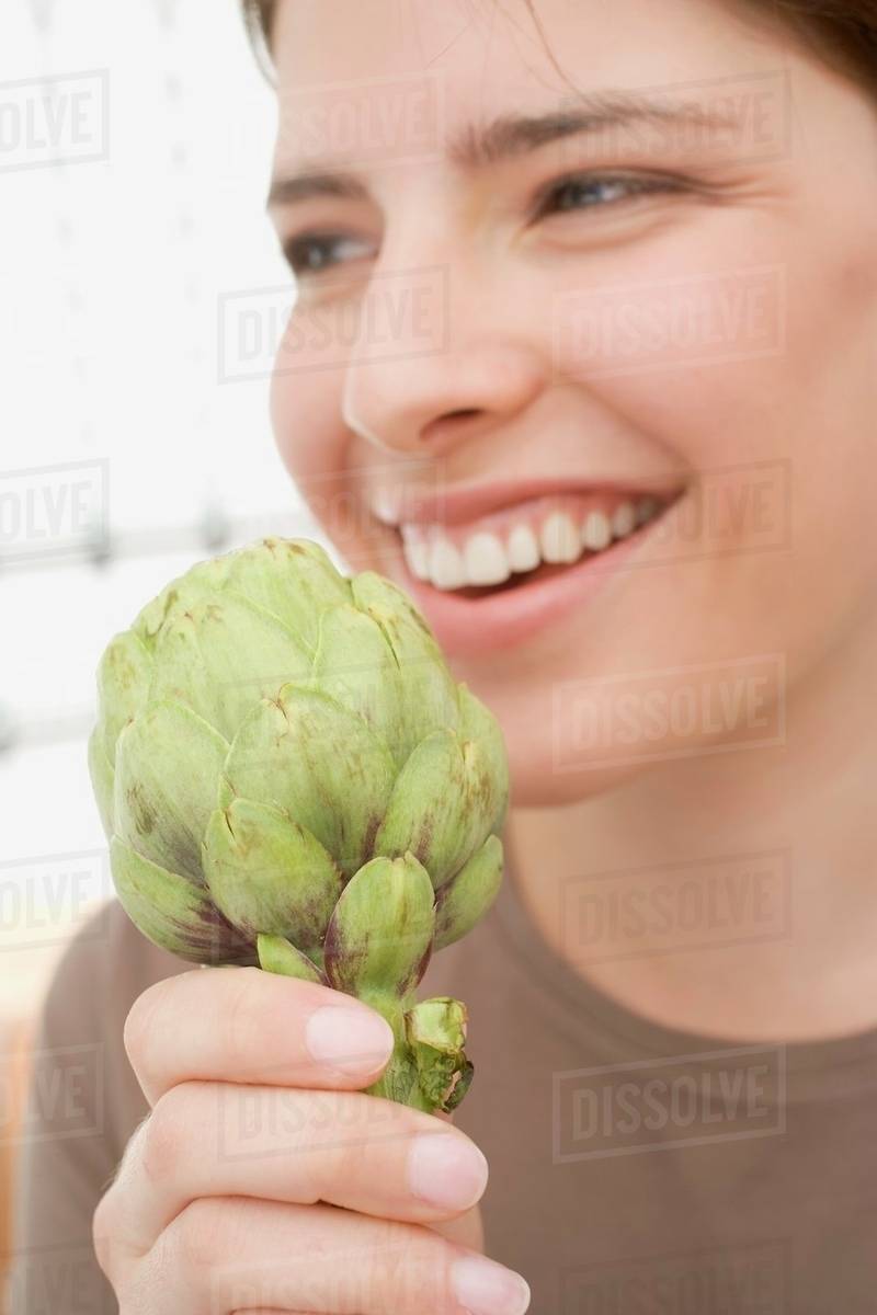 Young woman holding artichoke Stock Photo Dissolve