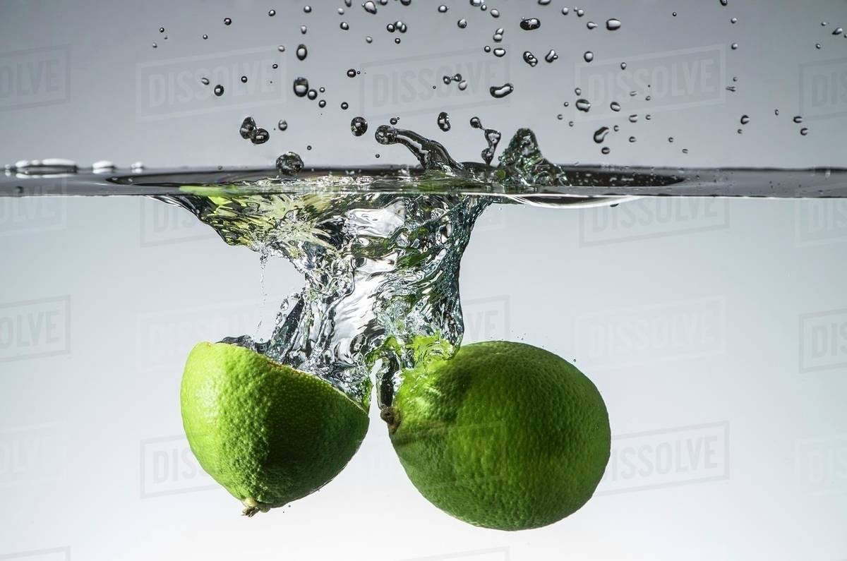 Limes falling into water Stock Photo Dissolve