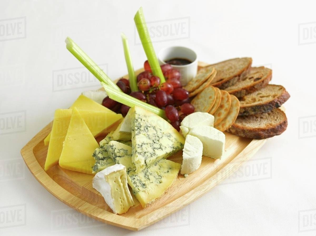 A cheese platter with bread, grapes and celery Stock Photo Dissolve