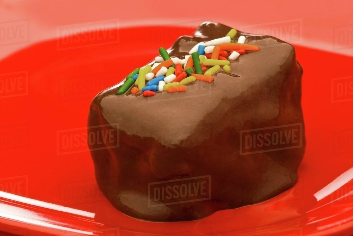 Chocolate Covered Brownie with Sprinkles on a Red Plate Stock Photo Dissolve