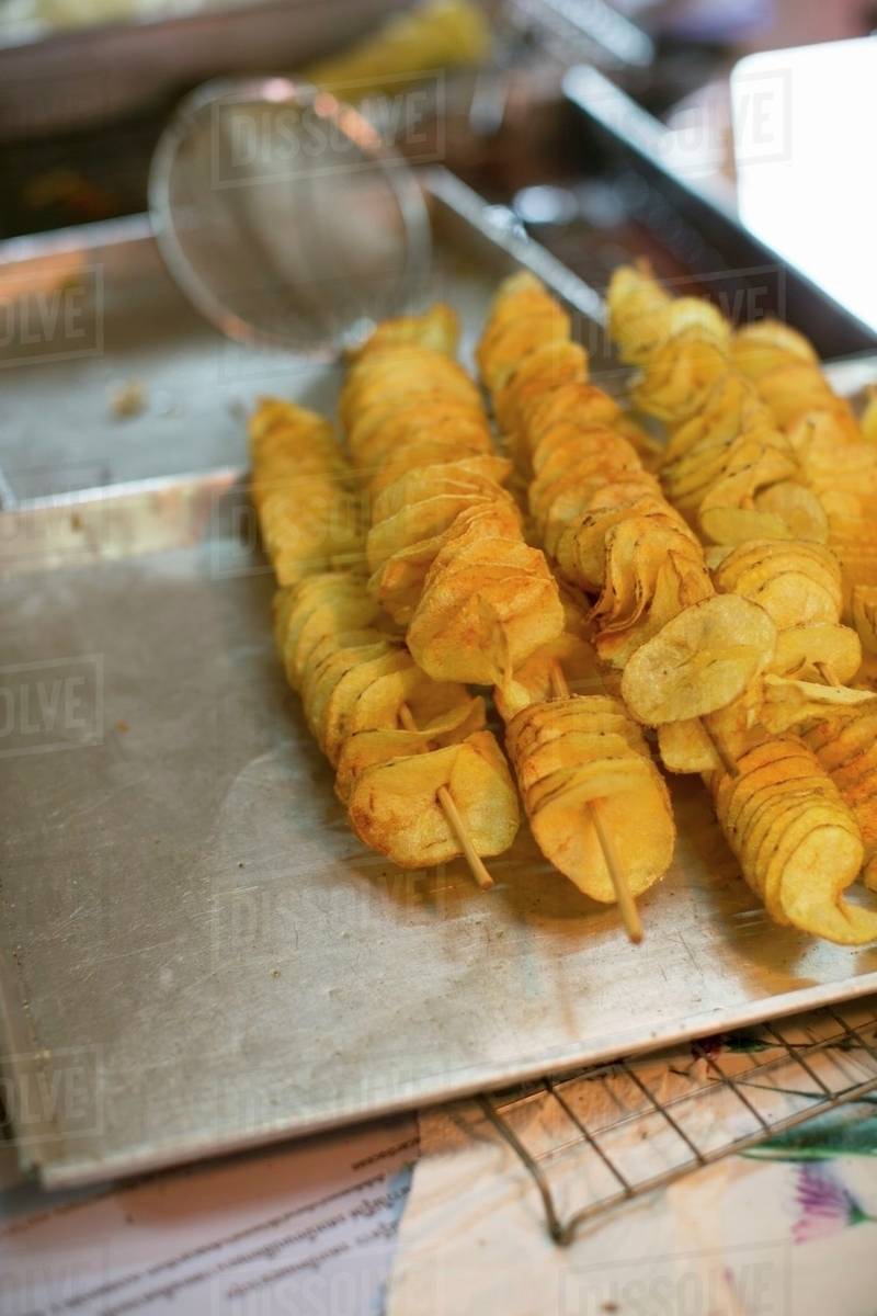 Deepfried potato chips on wooden skewers (Thailand) Stock Photo Dissolve