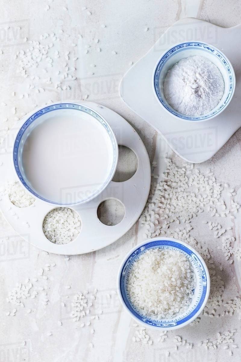 Bowls of rice milk, rice flour and rice grains on a marble surface