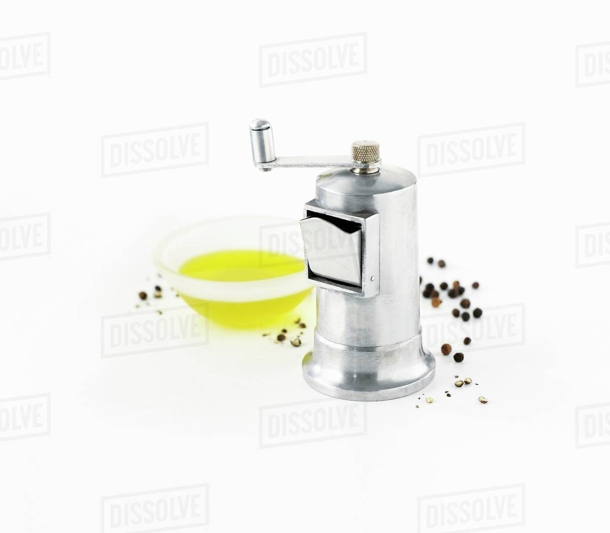 Pepper grinder, peppercorns and olive oil Stock Photo Dissolve
