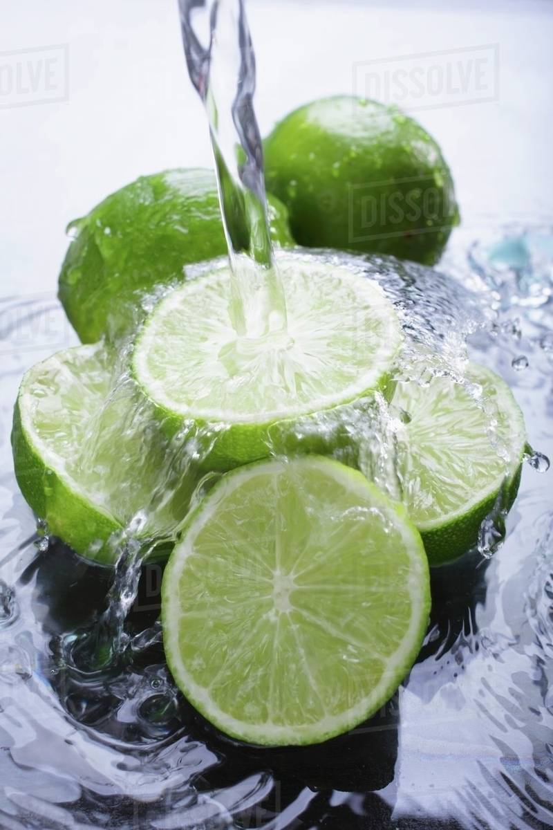 Limes in water with a jet of water Stock Photo Dissolve