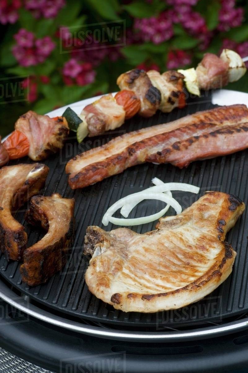 A pork chop, a kebab and a rib on a barbecue Stock Photo Dissolve