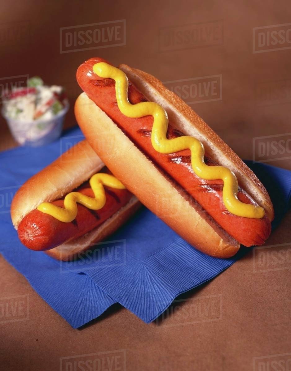 Two Grilled Hot Dogs on Buns with Mustard; On Blue Napkin; Cole Slaw