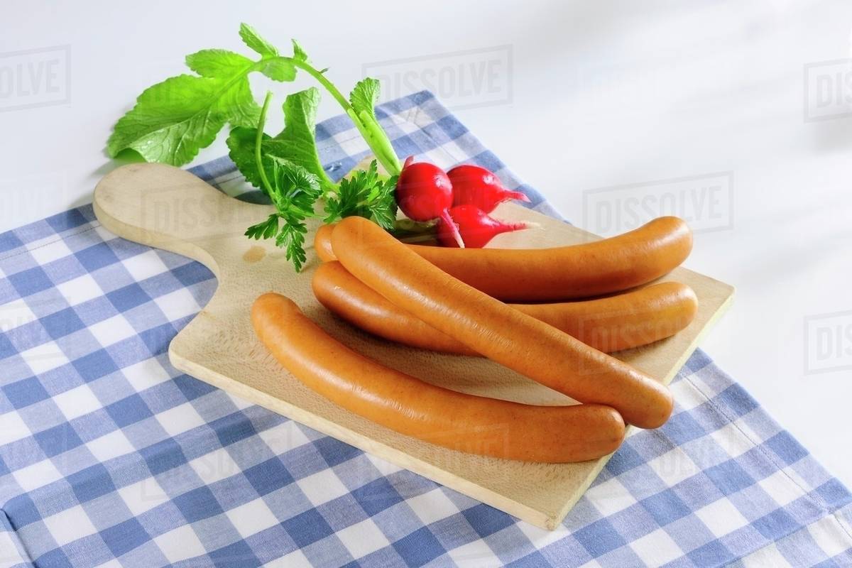 Hot dogs and radishes on a chopping board Stock Photo Dissolve
