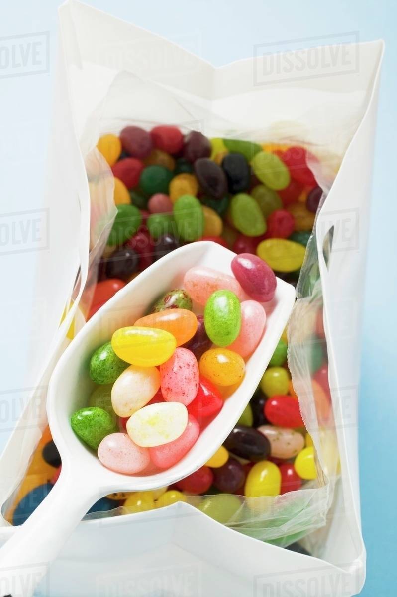 Coloured jelly beans in plastic bag with scoop Stock Photo Dissolve