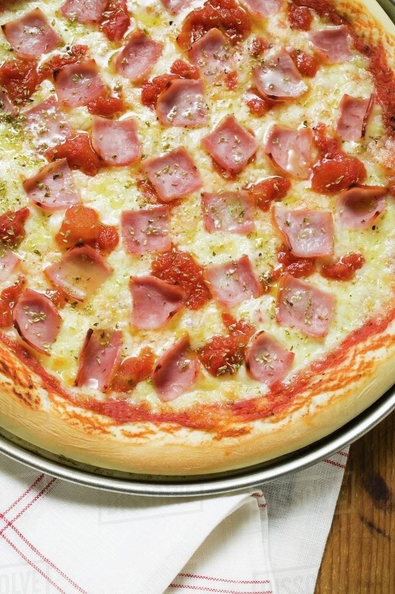 Ham, cheese and tomato pizza (detail) Stock Photo Dissolve