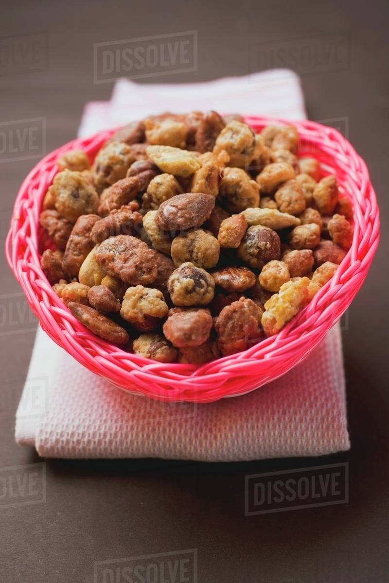 Mixed nuts to nibble in pink basket Stock Photo Dissolve