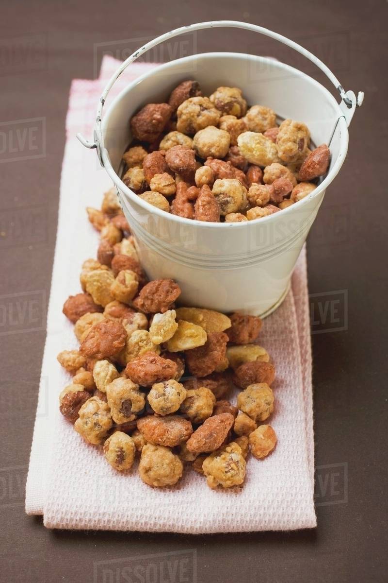 Mixed nuts to nibble in and beside white bucket Stock Photo Dissolve