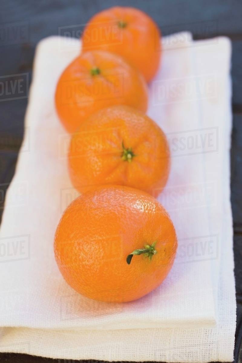 Four clementines on white cloth Stock Photo Dissolve