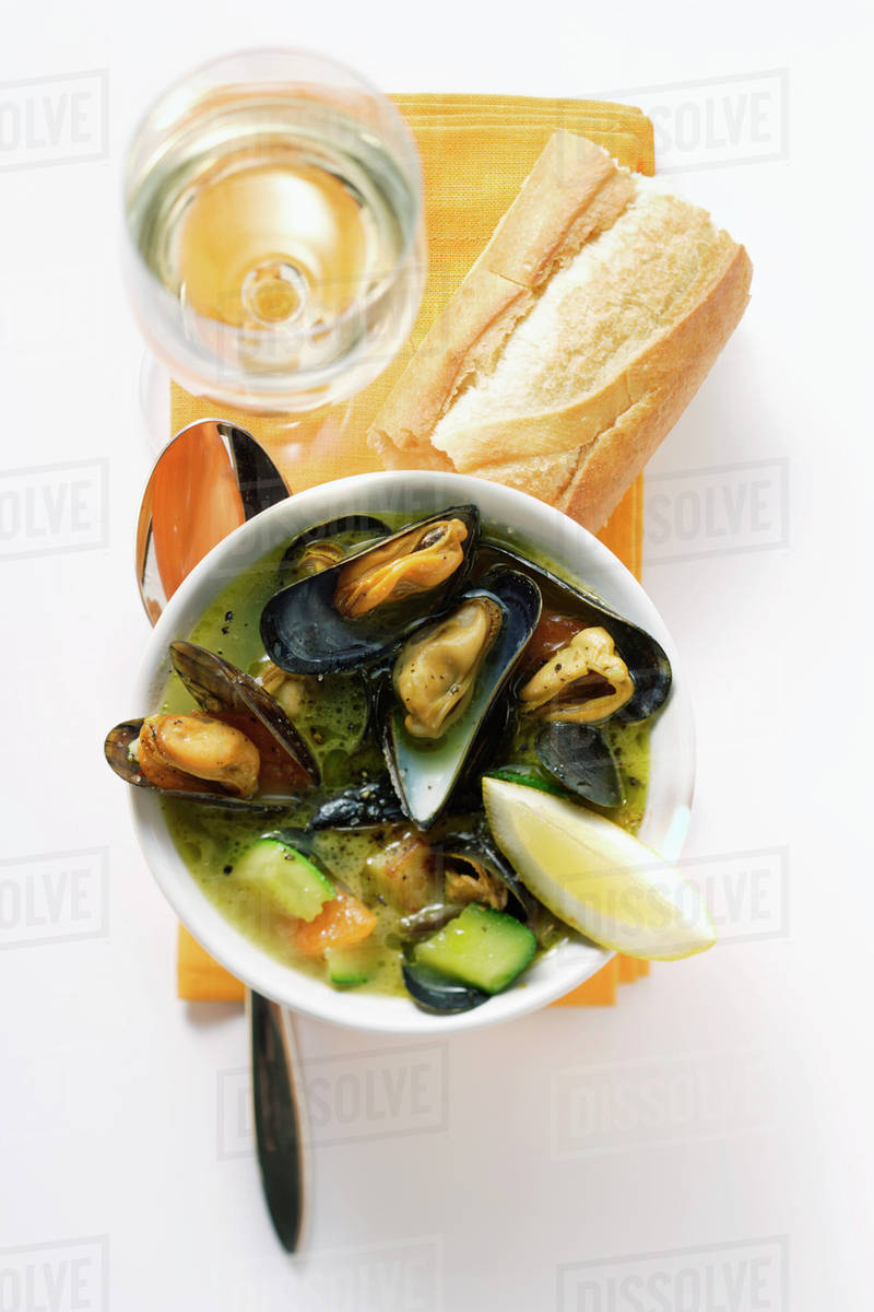 Mussel soup with courgettes; baguette Stock Photo Dissolve