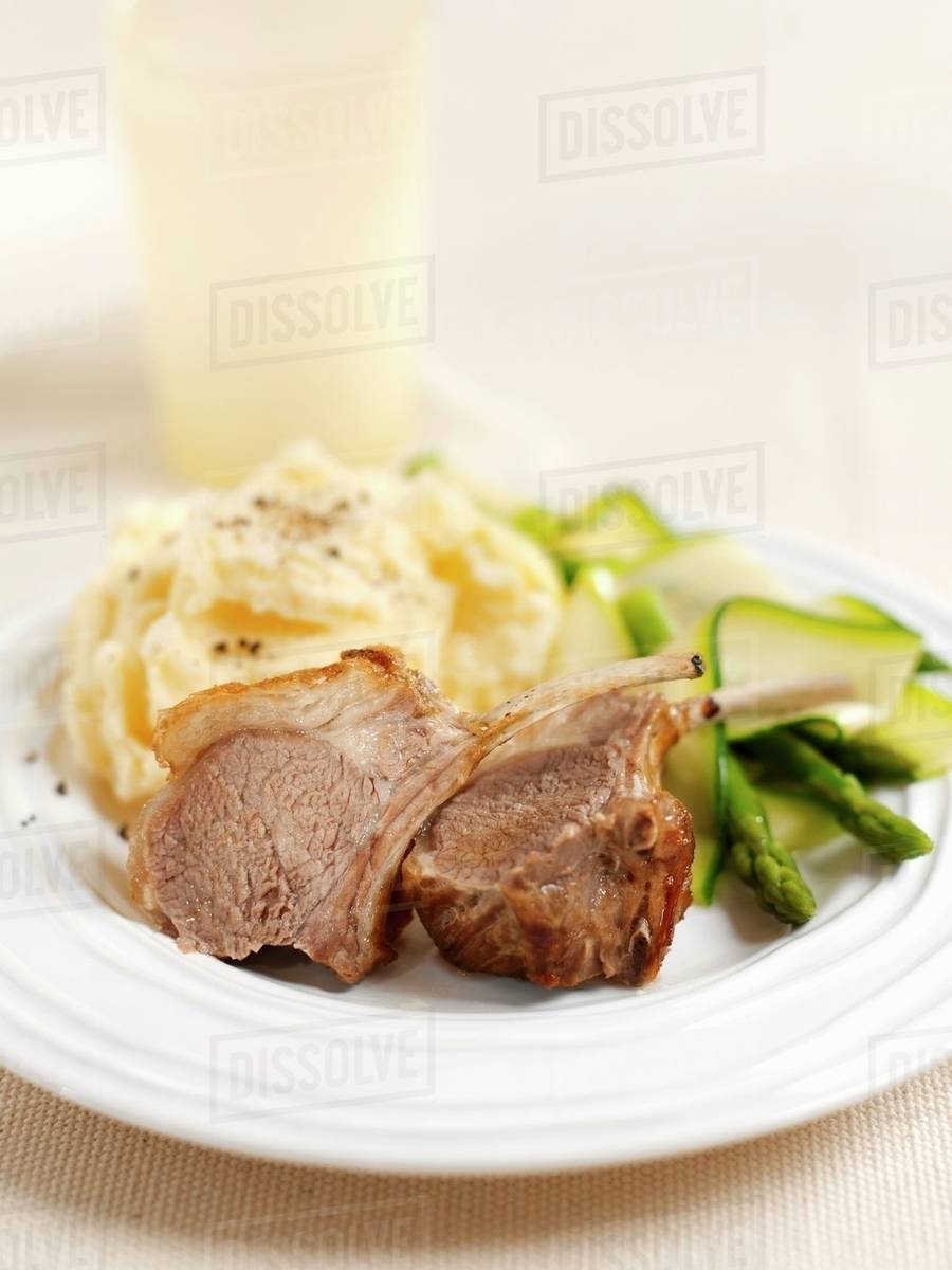 Lamb chops with mashed potato, courgettes and asparagus Stock Photo