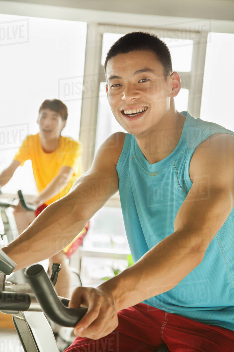 Young men on stationary bikes exercising in the gym Stock Photo