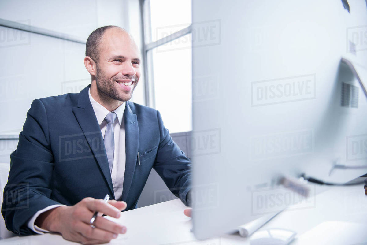 A professional man sitting in front of a computer in an office environment Royalty-free stock photo