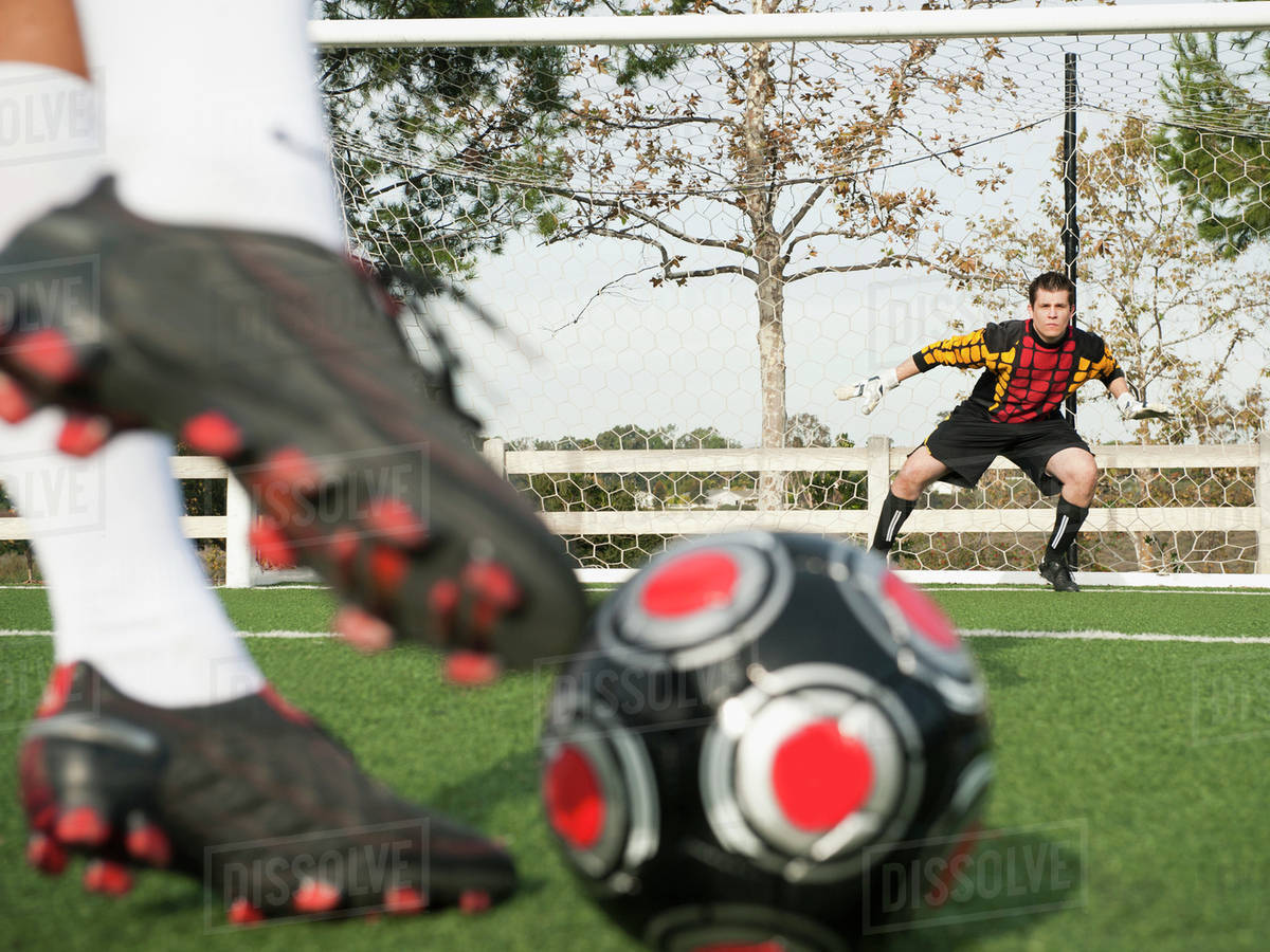 Soccer player kicking ball into goal on soccer field Stock Photo Dissolve